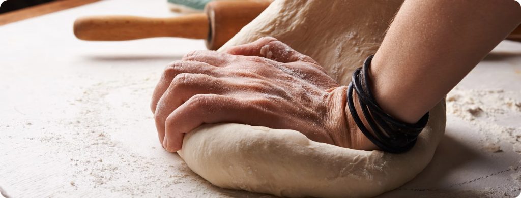 Personne en train de pétrir de la pâte sur un plan de travail